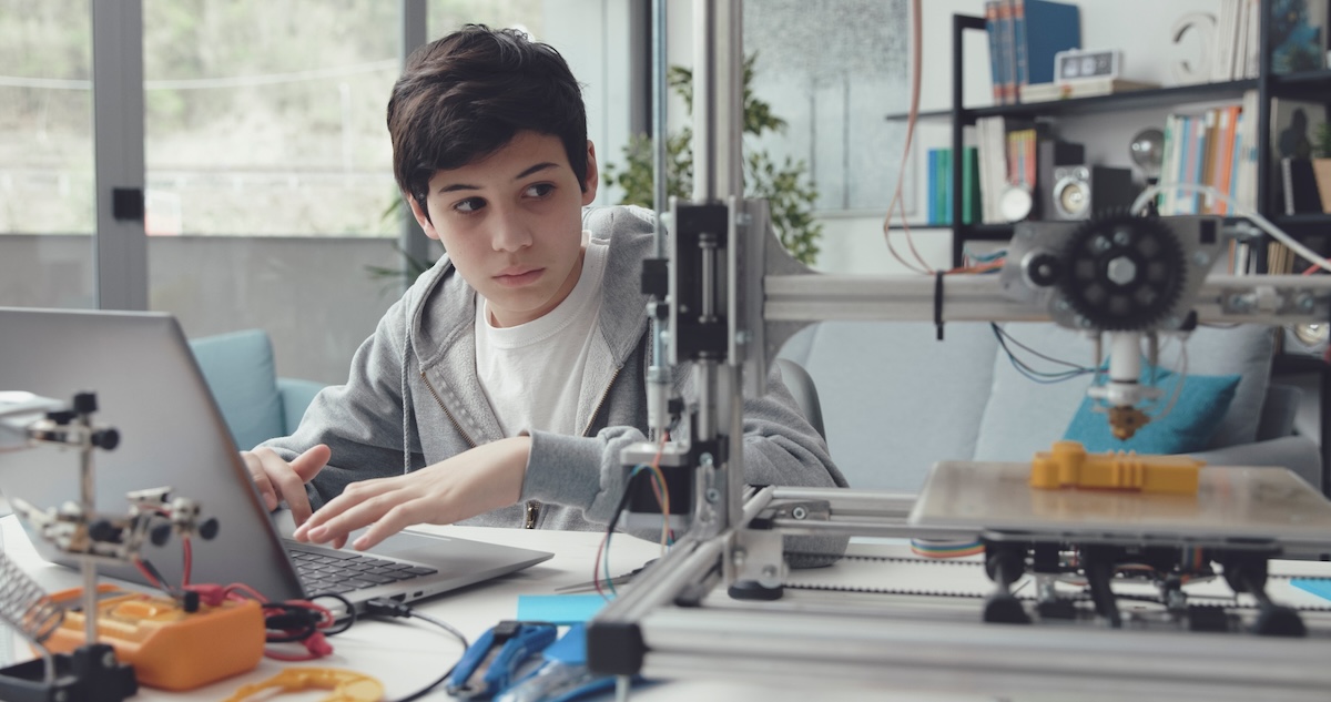 Student using a laptop beside a 3D printer to work with science data